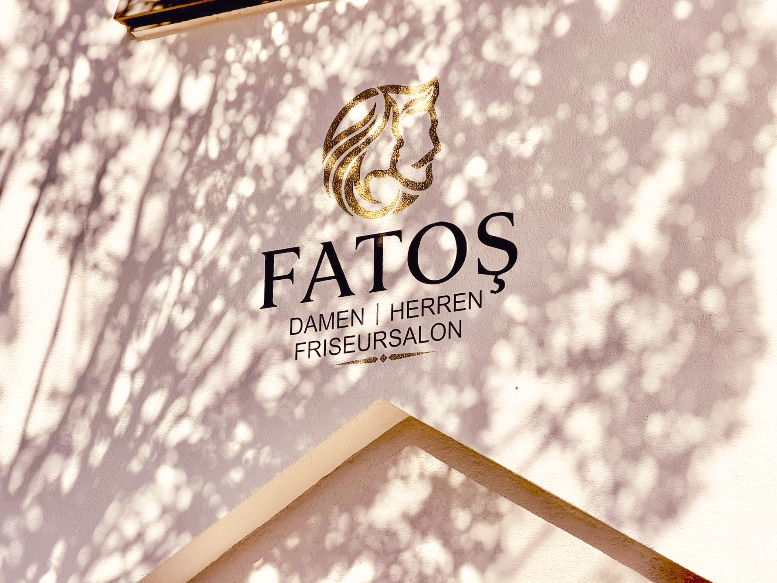 Goldenes FATOŞ-Logo an der Fassade mit Schattenspiel